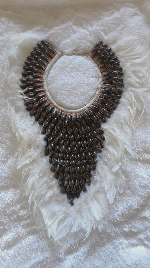 Collar Papua Native Warrior Plumas blancas y conchas marrones.